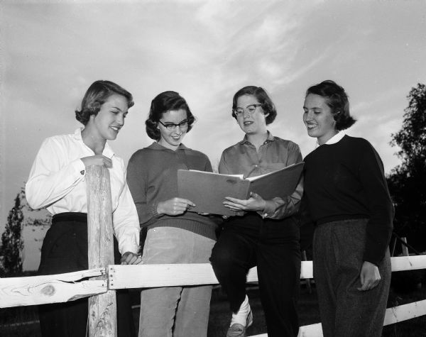 Outdoor group portrait of the officers of the Madison Hunt Club, a club for high school girls who like to ride horses. Left to right are: Marilyn Tormey of Wisconsin High School, Gretchen Loyster of Madison West High School, Karen Isaksen of Wisconsin High School, and Kathy Fleury of Edgewood High School.