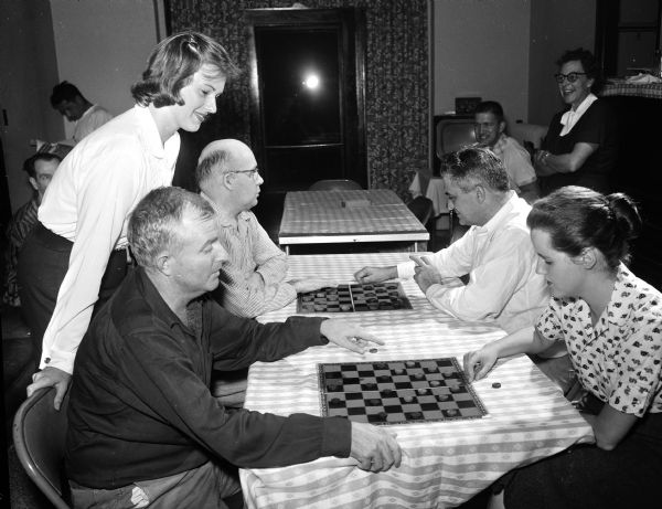 Two Methodist Hospital student nurses play checkers with patients at the hospital. At left is Susan Miller and at right is Mary Kane. They are participating in the state-wide aid project at various hospitals and welfare centers as part of Student Nurse Week. The patients, left to right, are: Robert Armiger of Cambria, Illinois; Charles Pawelek of Bradley, Ohio; and Ernest Mullins of Hillier, Kentucky.