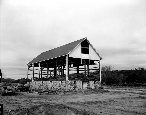 View of the John Castle dairy farm, located off North Sherman Avenue near Darwin Road. The barn has its wall boards removed revealing a wood beam frame, a roof and a rubble stone foundation with window and door openings. It stands in the center of the road being constructed between Packers Avenue and Northport Drive (with an extension to the west of Northport Drive). 

The Castle family sold the farm in 1913 to Joseph Hurrzak who lived there for two years until his death. A nephew of Hurrzak, Roger Moore, inherited the farm and retained ownership until it was sold to the city for right-of-way. The farm was north of Truax Field.
