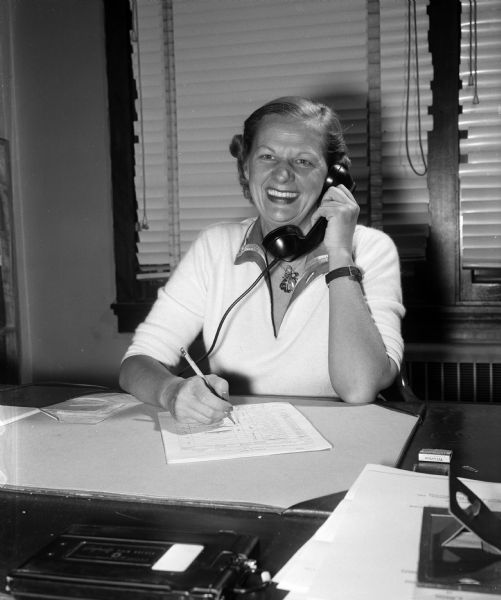 Miss Lillian Nitcher using the telephone. She is the associate executive secretary of the Community Welfare Council, and executive secretary of the Madison Youth Council. These agencies are Red Feather services that are supported by the United Givers' Fund.
