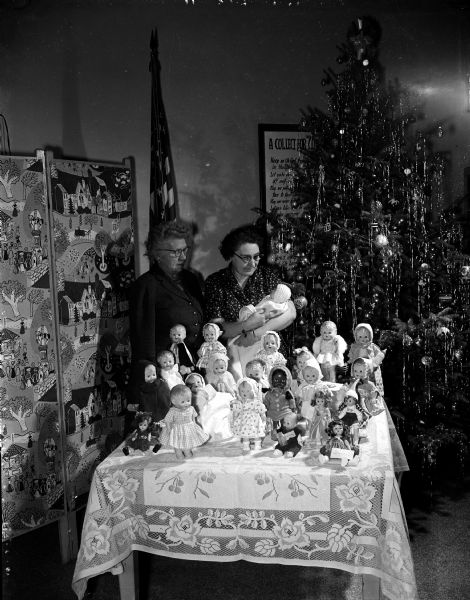 Gertrude Kepke, chairman of the social service department of the Woman's Club of Madison, and Lauraine Jensen, chairman of the club's orthopedic work, are shown with some of the dolls made by club members. Dolls will be distributed to patients at the Orthopedic Hospital.