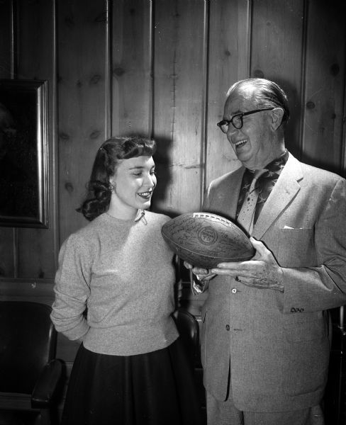 Joseph "Roundy" Coughlin holds an autographed football auctioned off at an Empty Stocking Club telethon. Standing with him is Patricia Cornwell, secretary to Roy Matson, editor of the <i>Wisconsin State Journal</i>.