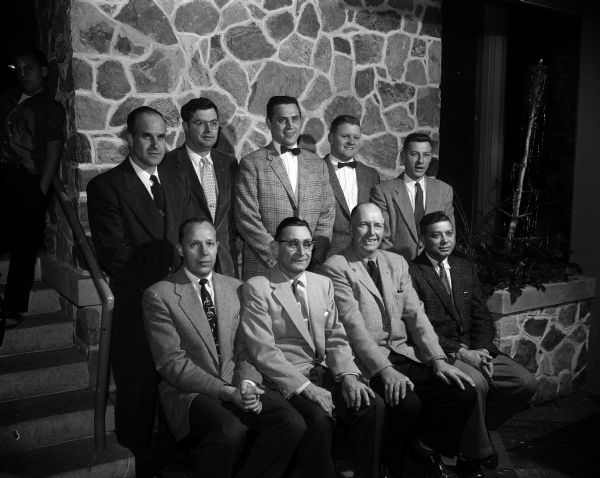 Group portrait of nine directors of the Blackhawk Ski Club. Seated in the first row are Stan DuRose, Harold (Blue) Schmelzer, I.R. Jacobson, and Sam LaBarro. Standing in the back row, are Art Daggett, Art Richardson, Hank Olshanski, Malcolm Kennedy, and William Duckwitz. They are sponsoring and planning the club's 11th annual ski jumping tournament to be held at Tomahawk Ridge, located two miles from Middleton.