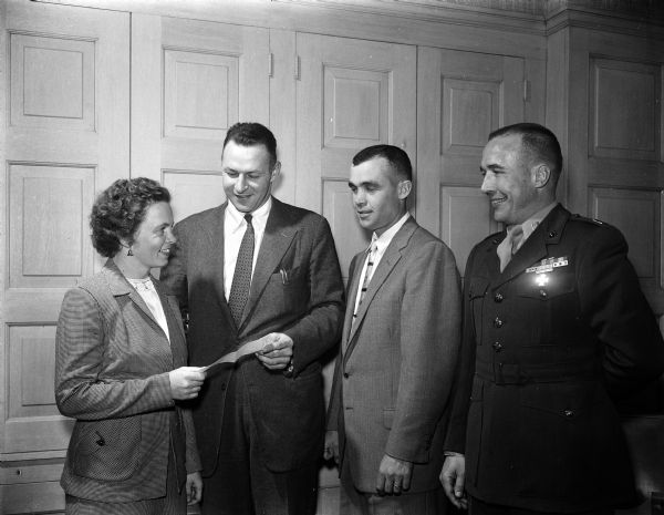 Phyllis Wikoff, director of the Empty Stocking Club, receives a check for $400 from Major Robert I. Perina, commanding officer of the 4th automatic-weapons battery of the Marine Reserves. Others are, left to right: Capt. Richard Lynch and Capt. Francis Gore. The Marine Reserves also donated toys totaling $600 in value.