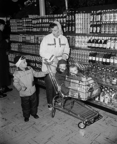 Mrs. Donald Tracy and her three sons, Douglas, Greg and Michael, use a shopping cart at the opening of the new Red Owl supermarket at 3535 East Washington Avenue.