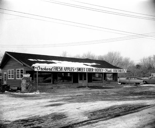 Exterior view of the newly opened orchard stand at Kapec Orchard on Verona Road. The sign across the front of the building advertises fresh apples, sweet cider, honey, and fresh vegtables.