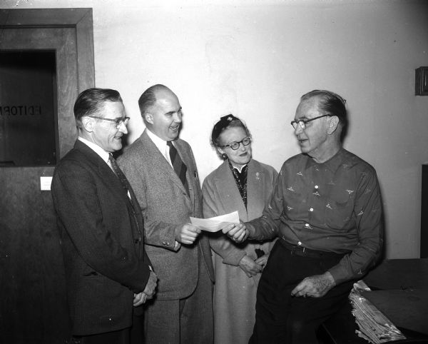 Shown left to right, are Barney Gill, James Geisler, chairman of "Roundy's Fun Fund" committee, Dagney Wang, recording secretary, and Joseph R. "Roundy" Coughlin.  They are holding up a banking receipt for $10,860, the total that was collected in 1957 through donations and fund raisers. Roundy's Fun Fund benefited handicapped and underprivileged children in the Madison area.