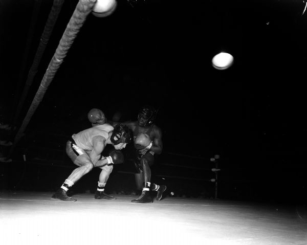 At left, Rollie Nesbit of Edgerton ducks a punch thrown by Brown McGhee of Memphis, Tennessee during the All-University Boxing finals. McGhee, a former Golden Gloves champion, won the championship.