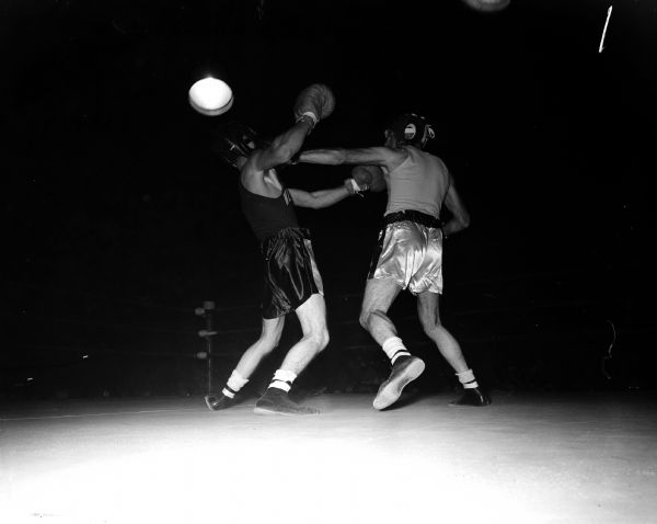 Action shot during the All-University boxing final at the University of Wisconsin. Ellis Gasser, Portage, lands a punch on Ed Sanborn of Madison. The match ended with a split decision.