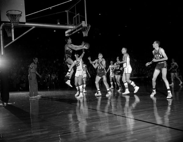Indiana's Jerry Thompson (#45) flips the ball underhand from behind the basket. Wisconsin players shown are Brian Kulas (#30), Bob Litzow (behind Kulas), and Bunky Holt (#4), Indiana's Pette Obremsky is #43. The Hoosiers won, 93-87. The photograph shows Thompson airborne higher than 12 inches.