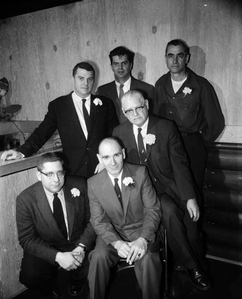 Group portrait of six men wearing suits with lapel corsages at the Ducks Unlimited Dinner. In the front row are Joseph Steuer, Angus Gavin and Woodbridge Bissell. In the back row are Toby Sherry, Ozzie Veerhusen, and Ed Bryant.
