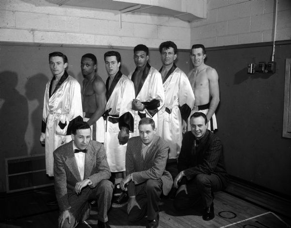 Group portrait of six of the seven Blessed Martin House boxers who will fight in the Rockford Golden Gloves district eliminations with their coaches. First row left to right:  Coaches Jackie Gibson, Bob Brigham, and George Holmes. Back row:  Tom Whalen, Jim Norton, Paul Schmelzer, Tony Pannel, Keith Chisman and Mel Hull. Missing from picture is Dave Kick.