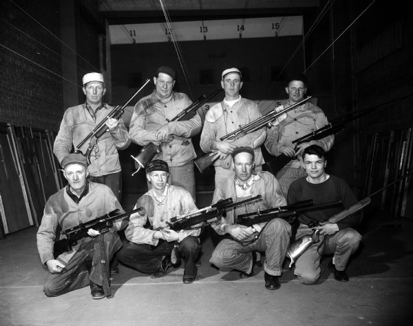 Group portrait of eight members of the Monroe Rifle Club. They took second place at the Southern Wisconsin Rifle League contest. They are holding their rifles.