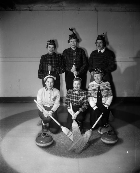 Group portrait of six members of the Madison Toories curling club who are serving on committees for the upcoming Badger Bonspiel. Front row, left to right: Gene Johnson, Mrs. Stephan F. Resan, and Frieda Waddell.  Back row, Mrs. H. Maxwell Manzer, Gertrude Timmerman, and Kathrine Lindsay.