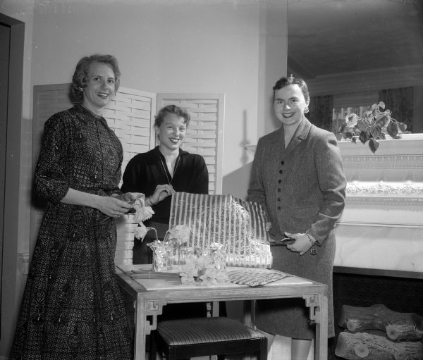 Chairmen of the Alpha Phi benefit dessert, bridge, style show, and bake sale are shown working on table centerpieces. They are Joan Kuypers, Sally Crownhart, and JoAnne Hedlin.