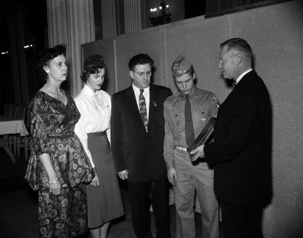 Forrest J. Carleen, Minneapolis (right), district representative of the Channel Master Corporation, is presented a plaque for being "the outstanding post in the eastern air defense post" of the Madison Civil Air Patrol by four representatives. Left to right are, Mrs. Maurice B. (Miriam)  Wigderson, 7 Frederick Circle; Constance Stolen, 1504 Edgehill Drive; Angus McVicar, 724 Conklin Place; and Stephen Bartholomew, 836 Oak Street. They represented the women, girls, men and boys in the GOC, respectively.