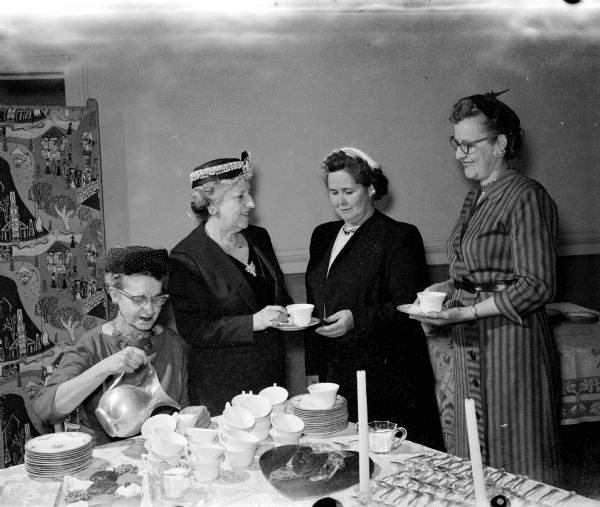 Two officers of the Madison Women's club serve refreshments to two foster parents. They are Marie Oakey, chairman of the Women's Club social service department; Jessie Briese, president of the club; and Mrs. Thorris Hofland and Mary Murphy.