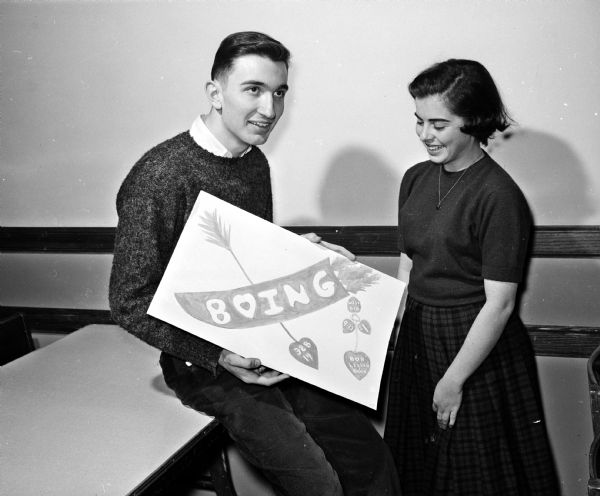 Dick Togstad and Judy Schwartz admire a poster for the West High School Valentine dance.