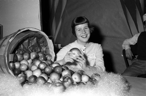 Edith Meinke from Ludinghausen, Germany, a Brittingham scholarship student at the University of Wisconsin, exhibiting some Wisconsin apples during the University's annual Farm and Home Week. Thomas Brittingham Jr. died April 16, 1960. The Brittingham Scholars program, founded in 1953 continued through 1962.