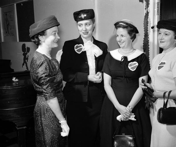 Four women attend a St. Valentine's Day tea given by the Truax Officer's Wives Club to welcome wives of officers newly assigned to Truax Field Air Force Base. At left is Anna Wise, wife of the commander of the 37th Air division. She greets, from left to right, Pascia Wittbrodt, Mrs. H.D. Champlin, and Mrs. Leo R. Scoles.