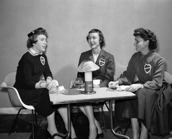 Three women attend a St. Valentine's Day tea given by the Truax Officer's Wives Club to welcome wives of officers newly assigned to Truax Field Air Force Base. They include, from left to right: Caroline Hyatt, Mrs. James G. Henry, and Mrs. Howard F. Brown.