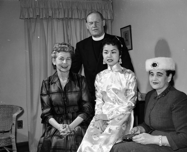 Songs from foreign lands were presented at a benefit musicale at the St. Francis House, 1001 University Avenue. The event was sponsored by  Episcopalians for the benefit of the Episcopalian Student center. Seated, left to right, are: Mrs. William Otto, resident housemother at St. Francis House; Mrs. Kim Hoang Miller, vocalist, shown in a white formal gown which she brought from her native Viet Nam; and Eleanor Nerdrum. Standing is the Rev. Gerald White of St. Francis House.