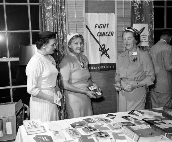 Three members of the Dane County board look over literature provided by the American Cancer Society for introduction into public schools. Left to right are: Mrs. June Metzen of Madison, Mrs. Ernest J. Schmitt of Waubesa Beach, and Mrs. Josephine Wheeler of Madison. Mrs. Wheeler directs the introduction of cancer education into public high schools.