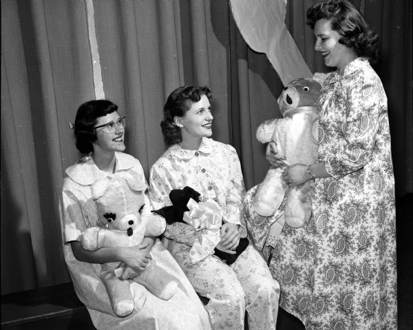 At a "We Saw You" fashion show, Miriam Hauri (left), Joan Faust, and Joanne Schoepp model pajamas they made. They are each holding a stuffed animal. The girls were Middleton High School students.