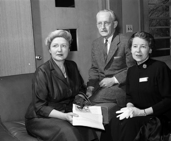 Two women and a man attend a gathering of the journalism society.