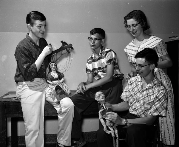 Three youth with marionettes preparing a puppet show for the Youth Summer Theater.  Left to right, Gibbs Burray, Ralph Retherford and Steve Birchall. Assistant director Mary Kate Lorenz is looking on.