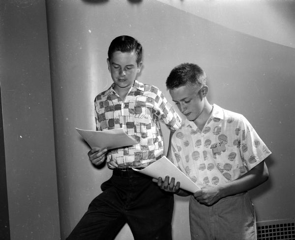 Two youth, Dave Jewett (left) and Steve Bracken, study scripts of a play that will be performed by the Youth Summer Theater on the Madison playgrounds.