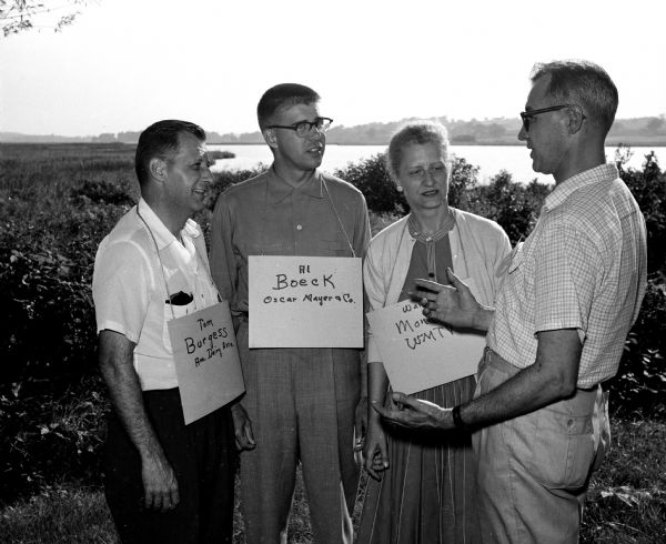 The Madison Press Club initiated 14 news and publicity people into the organization at a picnic on the grounds of the Fauerbach estate, located north of Madison. New initiates include, from left: Thomas Burgess, American Dairy Association; Al Boeck, Oscar Mayer; and Wanda Montz, WMTV, discussing the initiation with Leon Beier, membership chairman.