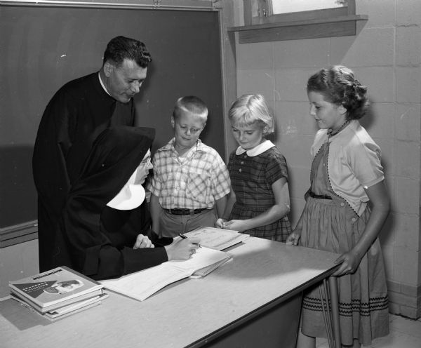 Rev. Edward Auchter, pastor of St. Mary of the Lake Catholic Church, and Sister Mary Martin get acquainted with three of the new fourth and fifth graders of St. Mary of the Lake Parish High School. The students include Bobby Watts, Donna Wipperfurth, and Susan Capaul.