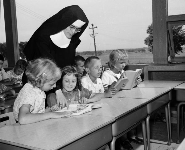 Sister Mary Clare, superior of St. Mary of the Lake and principal of the parish school, aids four third graders with their lessons. They include, from left, Barbara Hornung, Susan Ann Hoffman, Jimmy Grauvogl, and Susan Bethke.