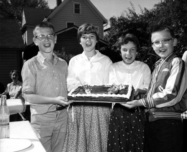 The Zimmerman twins, Lettie and Lloyd, celebrate their 11th birthday with 54 friends and 12 teachers at Lincoln School. Stephen Webster (left), Mary Pfister, Lyn Rejahl and Jon Seymour hold the birthday cake.