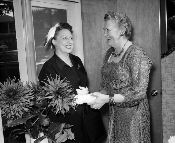 Helen, wife of Wisconsin's governor, Vernon W. Thomson attends a tea in honor of Helen E., wife of Edward T. Fairchild, former chief justice of the Wisconsin Supreme Court. She is being greeted by the hostess of the tea, Mary K., wife of the chief justice of the Wisconsin Supreme Court John E. Martin.