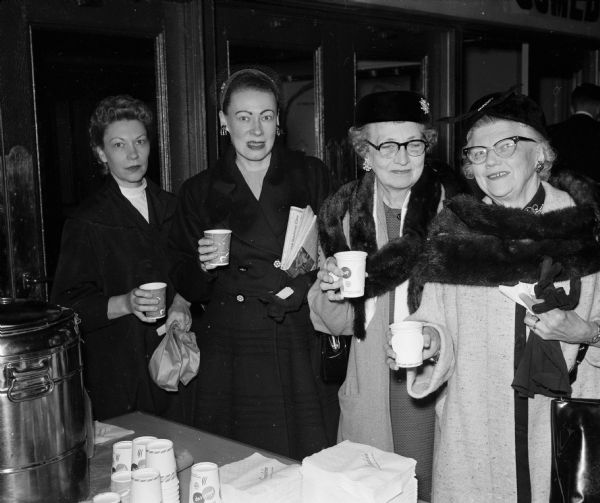 Four retail employes posing while holding paper coffee cups. They include (from left) Emma Sturm (Kessenich's), Irene Anderson (Hill's Beauty Salon, 202 State), Anna Steinborn (Hill's Beauty Salon), and Lillian Milroy (Simpson's).