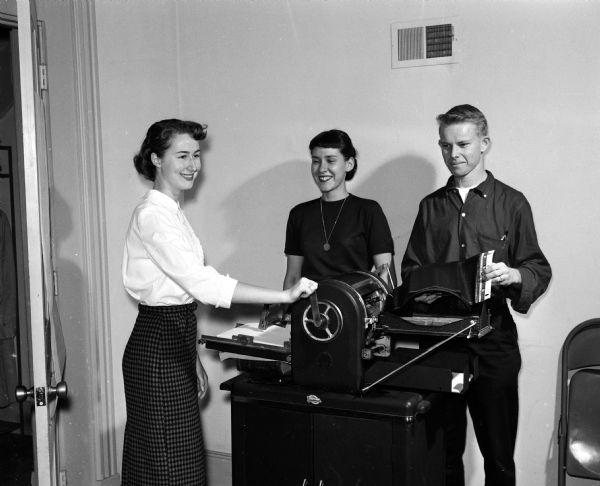 The publicity committee for Luther League Convention mimeographs programs for the event. They include, from left: Unison Reinke, Mary Anderson, and Franklin Swanson.
