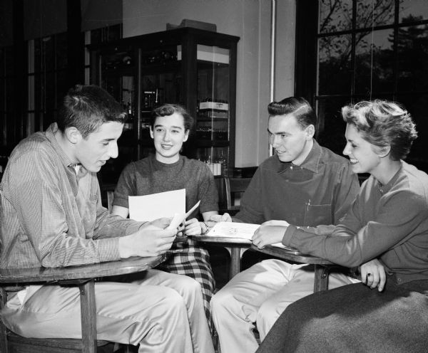 Edgewood High School students, (left to right): Paul Reisdorf, Mary Miller, Bob Faber, and Mary Boberschmidt look at a poster for Catholic Youth Week.