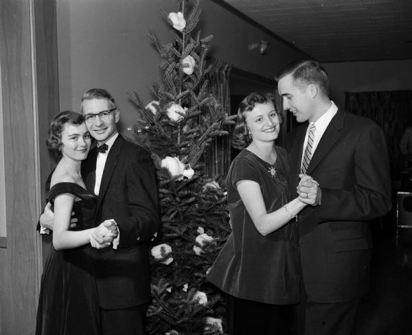 Two couples are shown dancing with a Christmas tree in the background. Left to right are: Nancy and Dr. William Hardin and Mrs. and Dr. Michael Lazor.