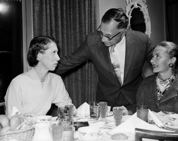 Louis Gardner (center) stands and chats with Bernie Reese (left) while his wife, Mrs. Gardner (right), gazes up at him. Louis Gardner was chairman of the board of Gardner Baking Co.