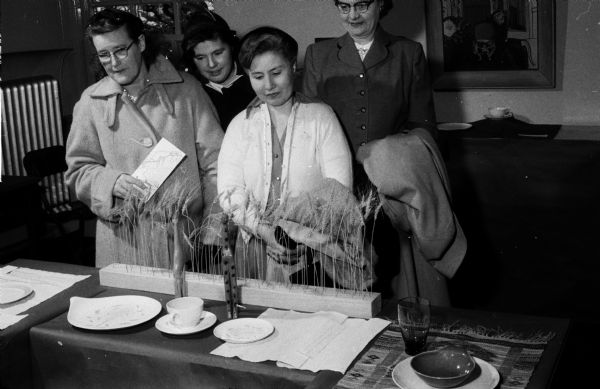 Attendees look at displays of hand-loomed placemats and tablecloths at Farm and Home Week at the University of Wisconsin. They include, left to right: Mrs. Rolland Coons, Mrs. Roy Pierstorff, Mrs. Walter Schlough and Myrtle Roeske.