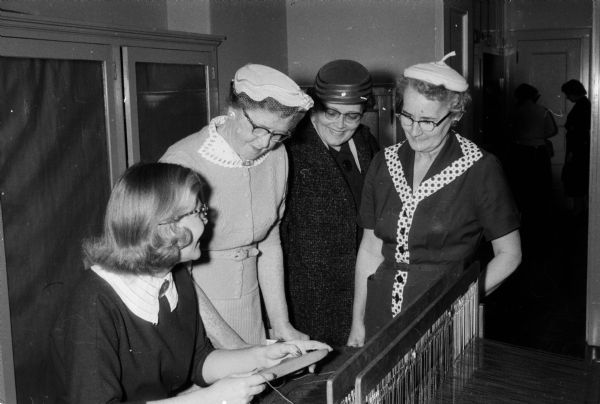 Mary Jean Stoddard demonstrates the art of weaving at the UW Farm and Home Exhibit. Watching her work (left to right) are: Mrs. Theodore Herwig (North Freedom), Mrs. Fred Deppeler (Juda), and Mrs. Howard Bystrom (St. Croix Falls).