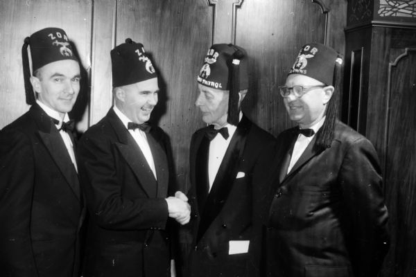 Zor Shrine members at the Potentate's Ball posing for a group portrait while wearing Shriner's hats. Left to right: Hal Metzen, James Geisler, Walter Hendrickson, and Olin Olson.