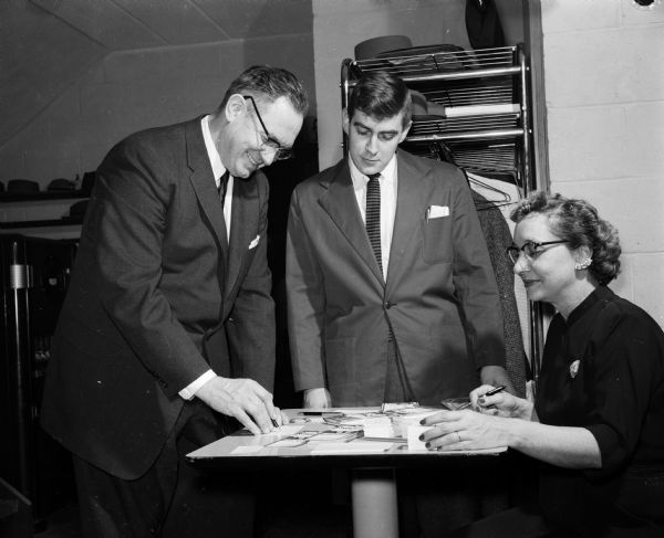 Melvin Dykman, left, and Ernest Clausen register for a Madison Restaurant Association open house. Nora McSherry, right, is assistant secretary of the group.