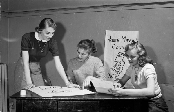 East Side Youth Mayor's Council members arrange for an election of a youth mayor and alderman. Publicity committee workers shown left to right: Delores Klubertanz, Jean Kleven, and Kathy Johnson.