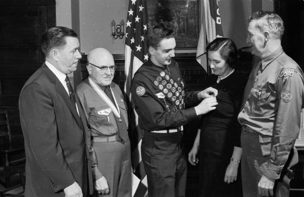Robert Whipple pins a miniature badge on his mother, Myrtle Whipple, after receiving an Eagle Scout Badge at Luther Memorial Church. Left to right: Rev. Franklin Swanson; George Morris; Myrtle and John Whipple.