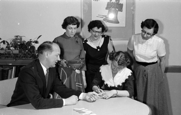 Mayor Ivan Nestingen draws names of groups to set the official order of competition for the Region 5 Sweet Adelines. Also seated is Mrs. Clifford Aagaard, publicity chairman. Standing, left to right, are: Dorothy Bleeker, chairman of judges; Mrs. C.A. Redders; and Kathryn Taylor, co-chairman of the event.
