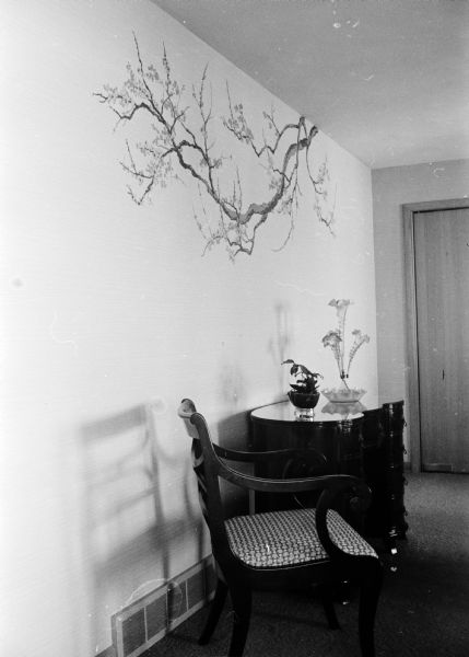 A Duncan Phyfe dining set in a dark finish stands In the dining room of the E.H. Karsten house at 2918 Waunona Way. The wallpaper is pale green with a flowering apple blossom motif on two of the walls.