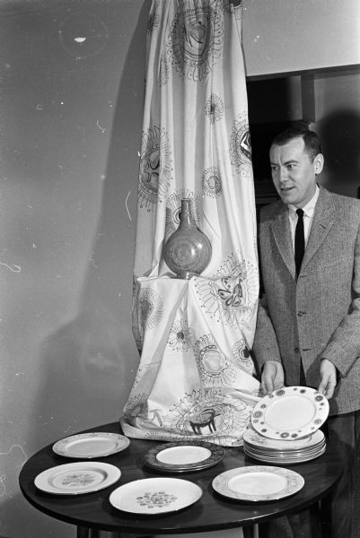 John Eustice poses with a display of his china patterns. A graduate of University of Wisconsin and New York State College of Ceramics, John specializes in the art of hand-decorated fine china. One of his designs was chosen for use in the White House by Mrs. Eisenhower.